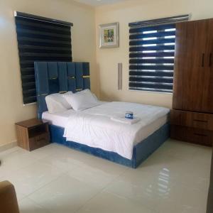 a bedroom with a bed with a blue headboard at DELCHIZZ Apartment in Mama