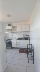 a kitchen with white cabinets and a white tile floor at Grande Aracaju ap executivo in São Cristóvão