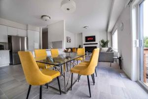 a dining room with a glass table and yellow chairs at Tranquil Lakeside Townhouse in Severn