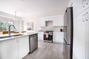 a kitchen with white cabinets and a black refrigerator at Tranquil Lakeside Townhouse in Severn