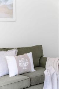 a couch with white and pink pillows on it at Mollymook Memories - close to beach & golf course in Mollymook