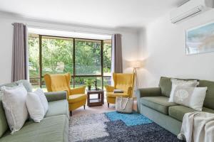 a living room with a green couch and yellow chairs at Mollymook Memories - close to beach & golf course in Mollymook