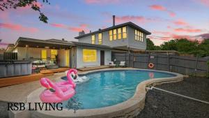 邓肯维尔Spacious 5BR Getaway with Pool的一座房子前的游泳池,里面有两个粉红色的火烈鸟