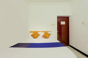 a bedroom with a white bed with blue and yellow pillows at SPOT ON JAYAM RESIDENCY in Chennai