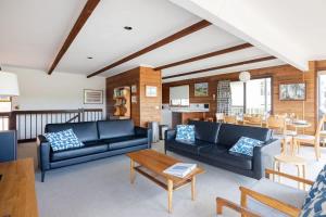 a living room with two couches and a table at Kelton Beach Haven - ocean views near golf in Mollymook