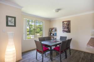 a dining room with a table and chairs and a window at Birchgrove Collers Beach - pet-friendly apartment in Mollymook