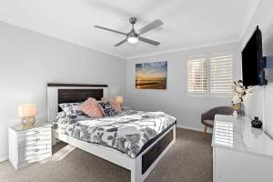 a white bedroom with a bed and a ceiling fan at Birchgrove Collers Beach - pet-friendly apartment in Mollymook