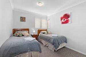 a bedroom with two beds and a window at Birchgrove Collers Beach - pet-friendly apartment in Mollymook +10 photos
