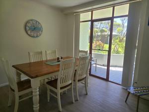 Una mesa de comedor con sillas y un reloj en la pared. en Fathoms 1 - 2BR beach resort apartment, en Mollymook