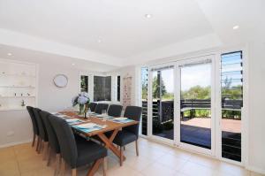 a dining room with a table and chairs and a balcony at Arcadia - large 4BR beach home & optional studio in Vincentia