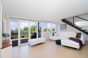 a living room with a white couch and a staircase at Arcadia - large 4BR beach home & optional studio in Vincentia