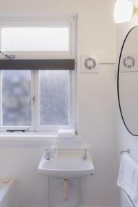 une salle de bain blanche avec un lavabo et une fenêtre dans l'établissement Tamar River Views Mid-Century Vibes, à Royal Park
