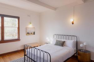 une chambre blanche avec un lit et une fenêtre dans l'établissement Tamar River Views Mid-Century Vibes, à Royal Park