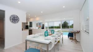 a white dining room with a white table and chairs at Bella Blu Beach House - direct beach access in Vincentia
