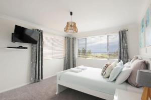 a white living room with a white couch and a window at Bella Blu Beach House - direct beach access in Vincentia +3 photos