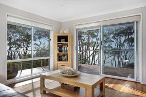 a living room with a table and large windows at Escape to Hyams Beach by Jervis Bay Rentals in Hyams Beach