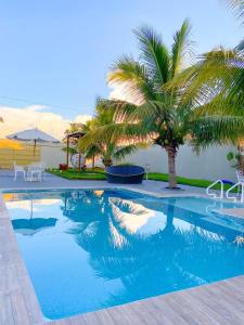 a swimming pool with a palm tree in the background at A Casa Paradisíaca Total Luxuoso Piscina Super Hiper Mega Quente 50 graus Aquecimento Elétrico , Sinuca e 5 Quartos Com Ar Condicionado Com Roupa de Cama e Banho in Caldas Novas