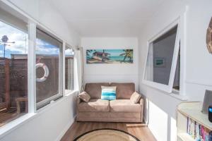 un salon avec une chaise et une fenêtre dans l'établissement Retro Beach Cottage - classic surf getaway, à Kioloa