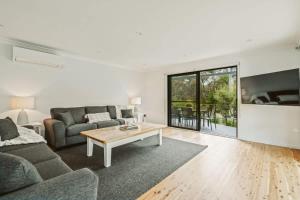 una sala de estar con un sofá y una mesa en Seahaven - pet-friendly retreat near Hyams Beach, en Hyams Beach