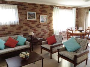 a living room with couches and a brick wall at Seascape Carroll Avenue - close to Mollymook Beach in Mollymook