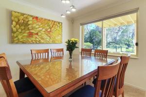 een eetkamer met een tafel en stoelen en een schilderij bij Pelican Beach House - 50m from inlet & playground in Narrawallee