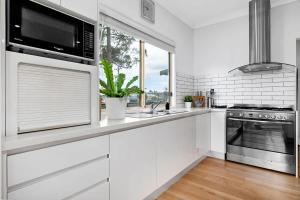 ビンセンチアにあるWhale Song - pet-friendly home steps to the beachのシンクと電子レンジを備えた白いキッチン