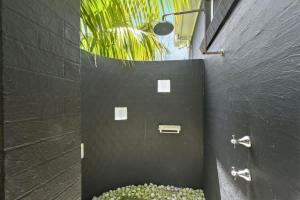 a bathroom with a black wall with a bowl of flowers at Sticks by the Sea - pet-friendly coastal home in Manyana