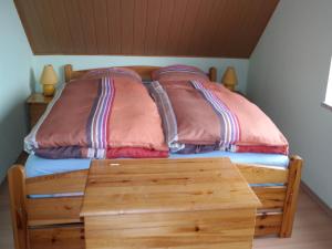 ベルガーエンデ・レートヴィッシュにあるFerienhaus mit Sauna und Whirlpoolの枕が2つと木製のテーブルが付いた木製のベッド