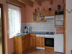 ベルガーエンデ・レートヴィッシュにあるFerienhaus mit Sauna und Whirlpoolのキッチン(木製キャビネット、白い電化製品付)