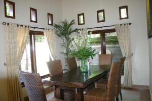 a dining room table with chairs and a vase of flowers at Puri Pondok Dawa Villa in Kusamba