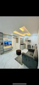 Una sala de estar con un sofá y un televisor de pantalla plana. en NgoZiLiving, en Lekki