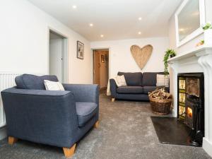 ein Wohnzimmer mit zwei Sofas und einem Kamin in der Unterkunft Pencefn Cottage in Llanddeiniolen