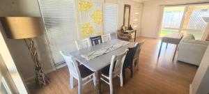 a dining table and chairs in a living room at Woodglen Coastal Retreat - pet-friendly beach home in Mollymook