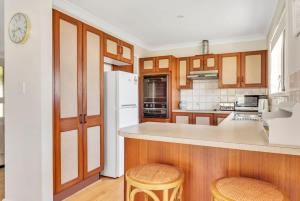 a kitchen with a white refrigerator and wooden cabinets at Woodglen Coastal Retreat - pet-friendly beach home in Mollymook
