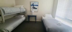 a bedroom with two bunk beds and a table at Woodglen Coastal Retreat - pet-friendly beach home in Mollymook +4 photos