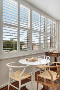 a white table and chairs in a room with windows at Bay Court Iii - Spacious Studio Near Hayes Beach in Sydney