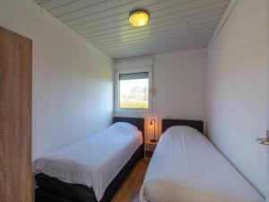 two beds in a small room with a window at Bungalow in Julianadorp near Sandy Beach in De Zandloper