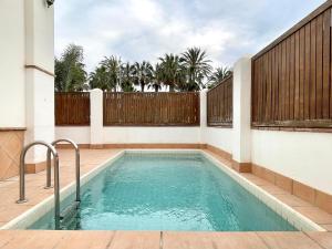 a swimming pool in a backyard with a wooden fence at Sunlit Villa near Golf in Motril