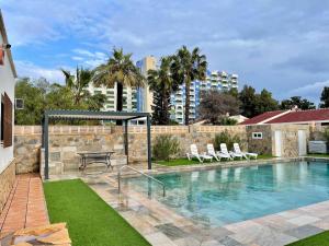einen Pool mit Stühlen, einem Tisch und einem Gebäude in der Unterkunft Villa in Roquetas near Beach & Pool in Roquetas de Mar