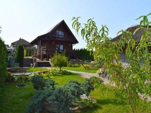 a log house with a garden in front of it at Holiday Home by Lake in Nowa Wioska in Lubrza