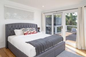 a bedroom with a large bed and a balcony at Aarini Cottage - The Ultimate Beachside Escape! in Macmasters Beach