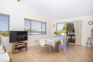 a dining room with a table and a flat screen tv at Aidan in Bawley Point +10 photos