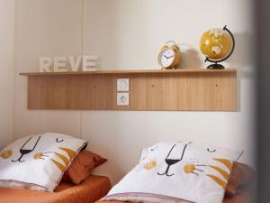 a bedroom with two pillows with a clock on a shelf at Mobil home 6 pers avec terrasse, 3 chambres - API-1-52-651 in Saint-Maurice-dʼIbie +24 photos