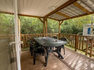 a patio with a table and chairs on a deck at Mobil home moderne avec terrasse pour 4 personnes - API-1-52-468 in Granges-Aumontzey
