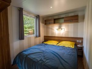 a bedroom with a bed with blue sheets and yellow pillows at Mobil home moderne avec terrasse pour 4 personnes - API-1-52-468 in Granges-Aumontzey +28 photos
