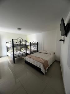 a bedroom with two beds and a flat screen tv at Hotel Plaza Colonial in Valledupar