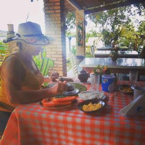 a man in a hat sitting at a table with food at Club Manguaba Beira Rio Mar in Japaratinga