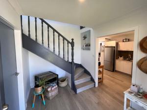 a living room with a staircase and a kitchen at Souira Beach House in Manyana +12 photos