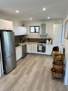 a kitchen with white cabinets and a stainless steel refrigerator at Souira Beach House in Manyana