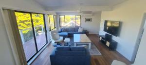 a living room with a blue couch and a tv at Scotts Ocean View - 6BR beachside Mollymook home in Mollymook